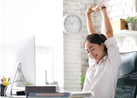 Woman stretching from office desk with decreased back pain