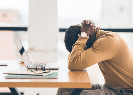 mean leans over desk in fatigue