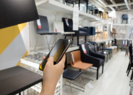 someone shops online via their mobile phone in a furniture store