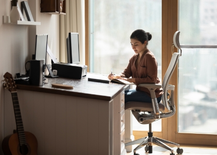 a woman sits at a desk with pristine posture in an ergonomic chair