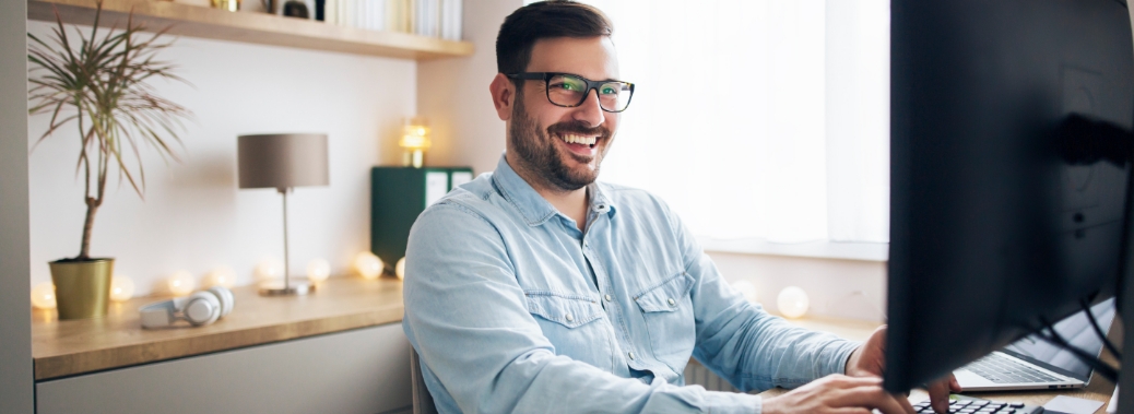 a man in glasses smiles at his desk