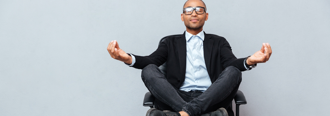 Relaxed african young man sitting and meditating on office chair